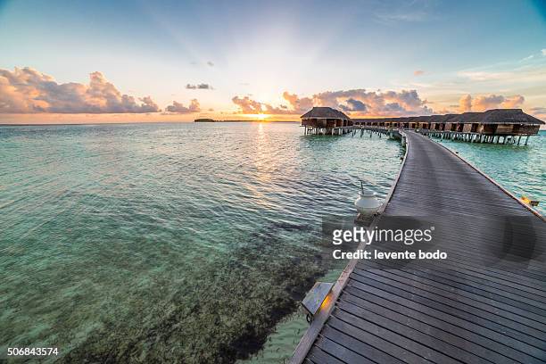sunset on maldives island, water villas resort - ponton mer photos et images de collection