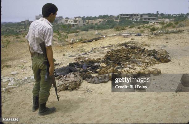 Shiite Amal Militiaman views corpses he says are Moslems kidnapped and killed by Christian Leb. Forces Militia.