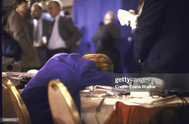 An exhausted woman reporter slumping over a table at the Marriott press center at the end of the US-Russian summit.