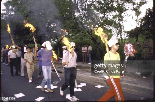 Leftist university students wearing face masks and carrying flaming torches while protesting at the US Embassy.