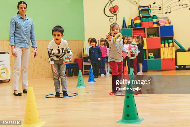 group of children playing with their teacher in kindergarten - ring toss bildbanksfoton och bilder