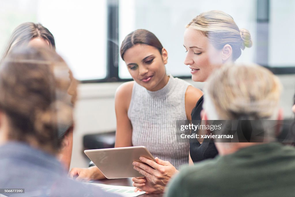 Donna d'affari alla ricerca di una tavoletta digitale in una riunione
