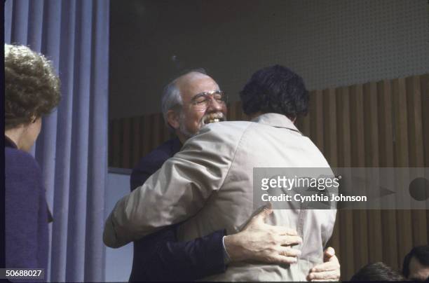Ex- hostages Jeremy Levin and Father Lawrence Martin Jenco hugging as Chairman of No Greater Love Carmella Laspada , stands by.