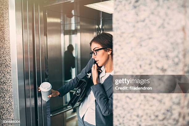 businesswoman on the phone in the elevator - elevator doors stock pictures, royalty-free photos & images