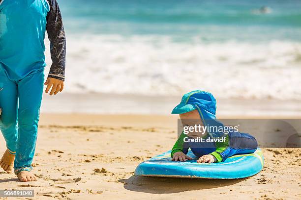 babymode – jungen scheinbar surfen sie am strand - australia holiday stock-fotos und bilder