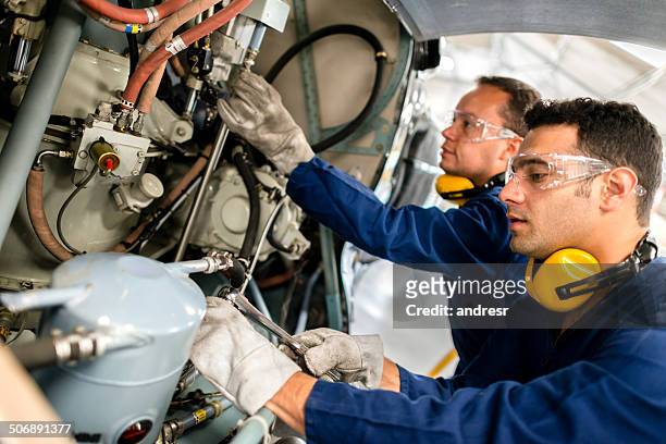 mechanics fixing a helicopter - vliegtuigmonteur stockfoto's en -beelden
