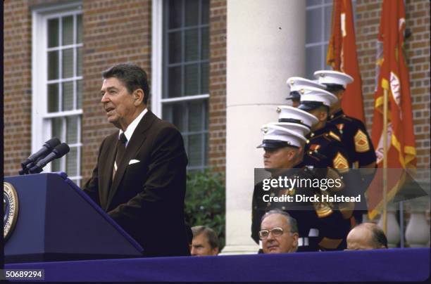 Pres. Ronald W. Reagan addressing graduating class at Parris Island Marine Corps Training Center with Sen. Jesse A. Helms seated behind him.