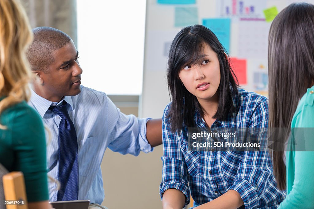 African American man comforts Asian woman in support group therapy