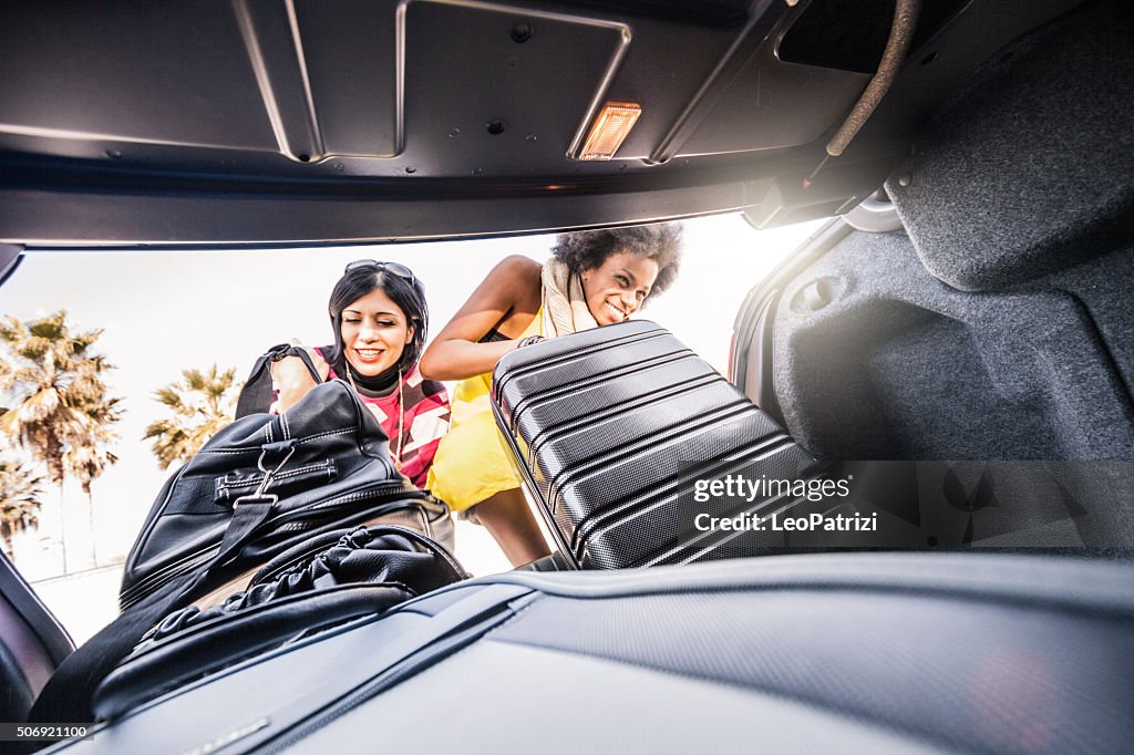 Women friends loading the car to start a great vacation