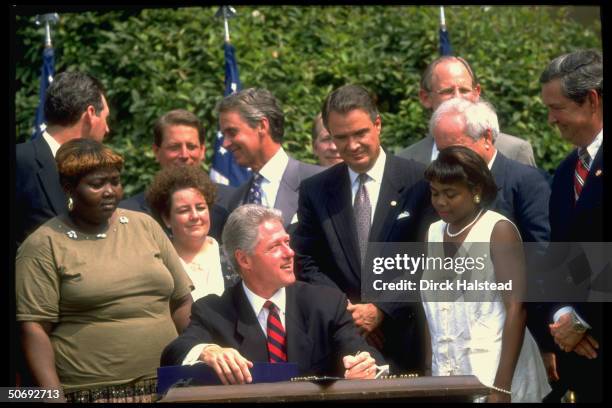 Pres. Bill Clinton signing controversial welfare reform bill in White House Rose Garden, w. Former welfare recipients, VP Gore , Sen. John Breaux &...