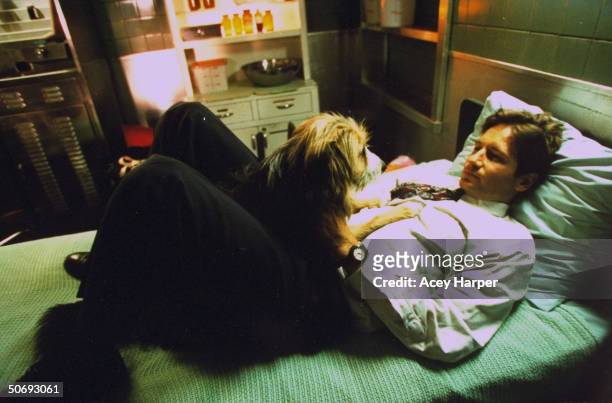 David Duchovny, co-star of cult TV series The X-Files, lying on bed w. Pet dog in between scenes on the set of the show.