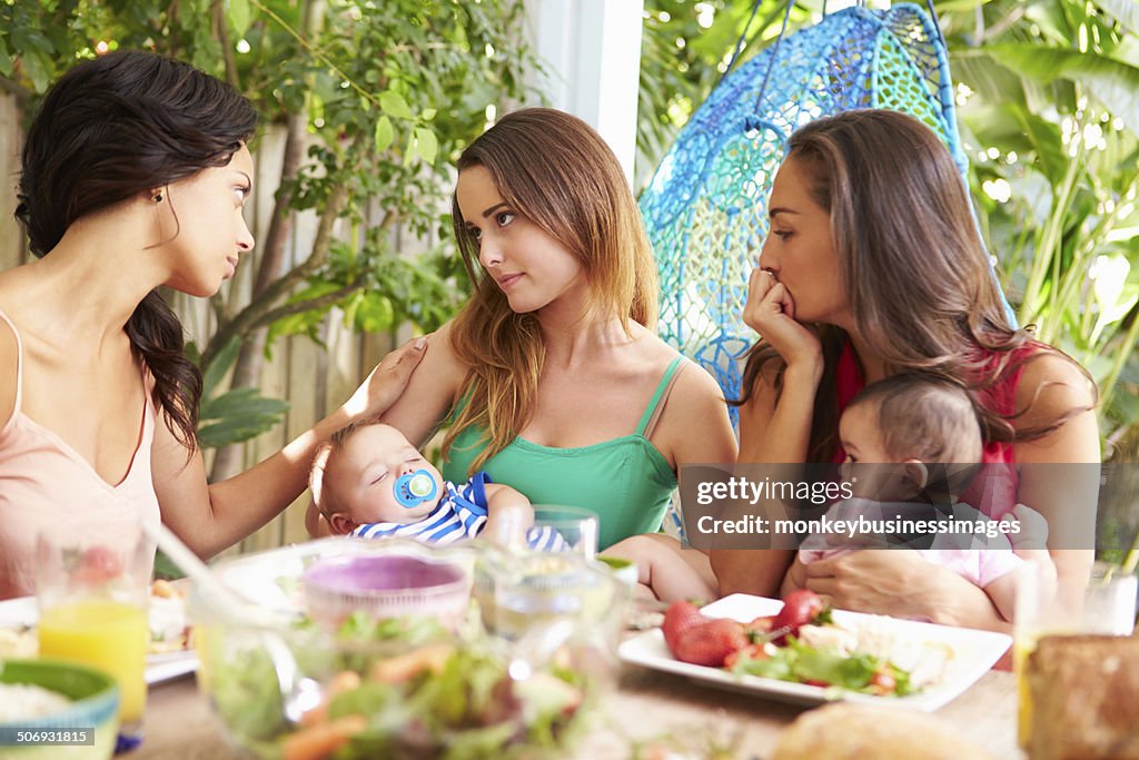 Depressed Mother With Baby Talking To Friends