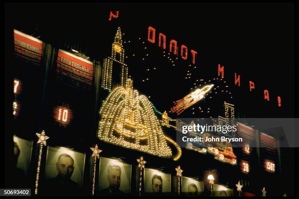 Display of electric lights featuring Sputnik, fountain, Moscow University, above pictures of former Soviet leaders during 40th anniversary...