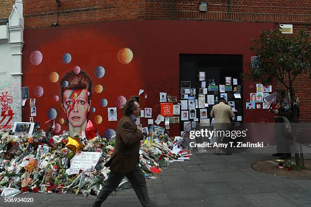 Man walks by the flowers, letters and other items left on a mound continue to grow two weeks after the death of Brixton born English singer,...