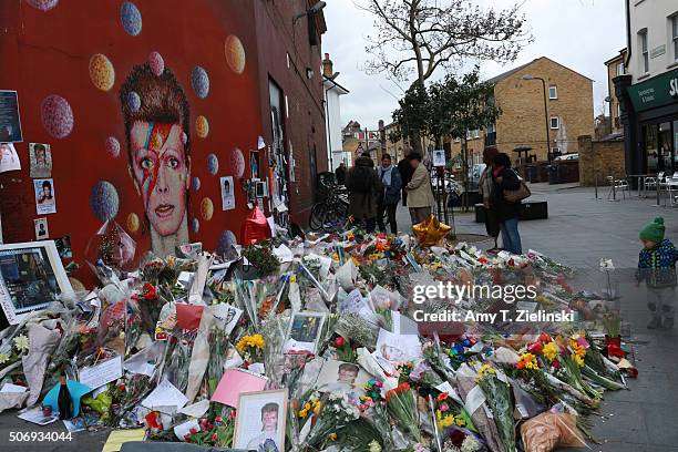 People looks at the writings on the wall near the flowers, letters and other items left on a mound continue to grow two weeks after the death of...