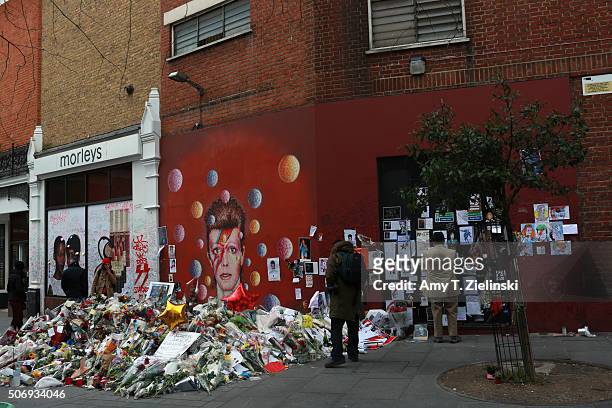 People read and pay their respects near the flowers, letters and other items left on a mound continue to grow two weeks after the death of Brixton...