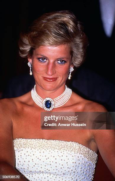 Diana, Princess of Wales wearing a white strapless dress, embroidered with pearls, designed by Catherine Walker and a pearl and sapphire choker,...