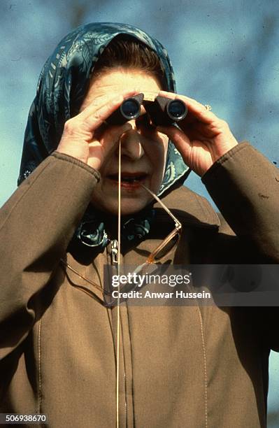 Queen Elizabeth ll watches the cross country event through binoculars at Badminton Horse Trials on April 19, 1980 in Badminton, England.