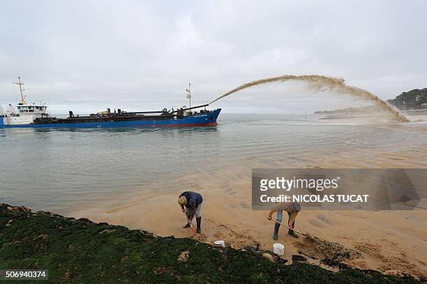 Men dig in the sand as the dredger "Cotes de Bretagne" shoots sand onto a beach of Pyla-sur-Mer in La Teste-de-Buch in Arcachon Bay. The boat, from...