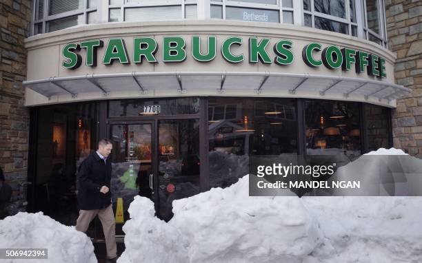 Man walks past a Starbucks Coffee shop behind a large pile of snow in Bethesda, Maryland on January 26, 2016. The US capital remained crippled...