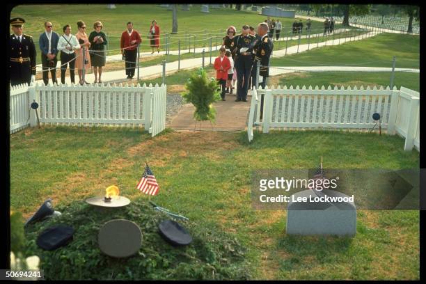 Visitors at grave site paying respects to slain President John F. Kennedy on first birthday after the assassination as military guards stand by.