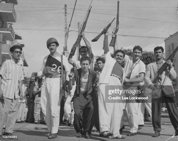 Pro-Castro Cuban political prisoners w. Rifles raised in air joyously celebrating liberation as victorious rebel forces arrive in Havana.