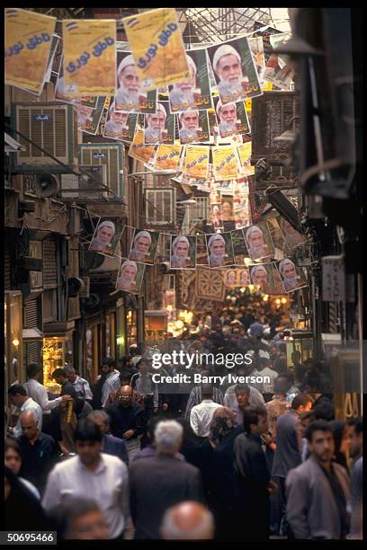 Crowded bazaar w. Presidential election campaign posters picturing conservative cleric candidate Ali Akbar Nateq-Noori strung overhead.