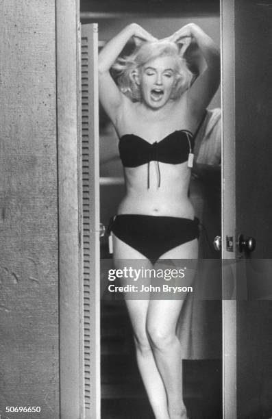 Actress Marilyn Monroe posing for husband Arthur Miller fr. In dressing rm. Doorway after putting on sexy bikini bathing suit she purchased, w. The...