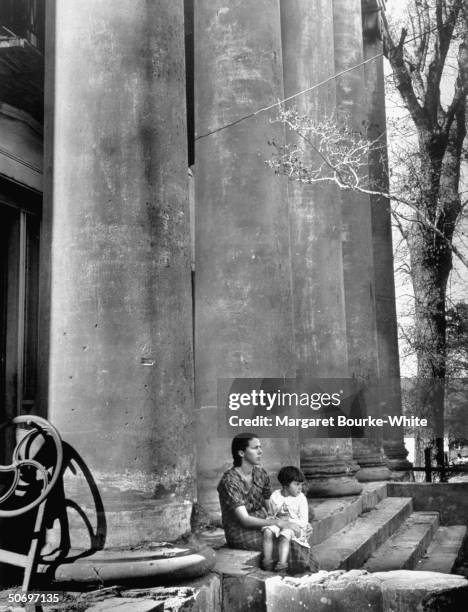 Sharecropper's wife & young daughter sitting on the steps of run-down, nearly abandoned, antebellum mansion in which they rent 2 rooms for $5 a...