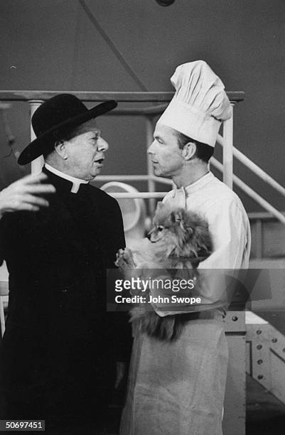 Frank Sinatra disguised as chef, holding Pomeranian dog w. Bert Lahr in priest's costume during preliminary rehearsal for Cole Porter's musical...