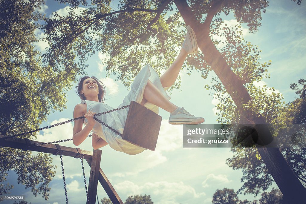 Happy young woman smiling on swing