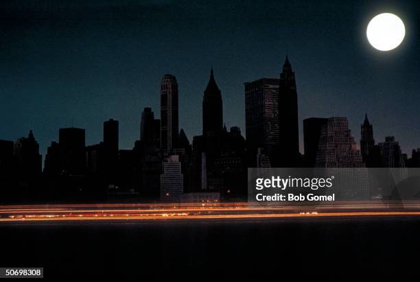 Bright full moon over darkened New York City skyline during massive East Coast blackout affecting 80,000 square miles.