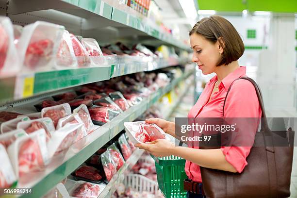 mulher escolhe carne na loja - talhante imagens e fotografias de stock