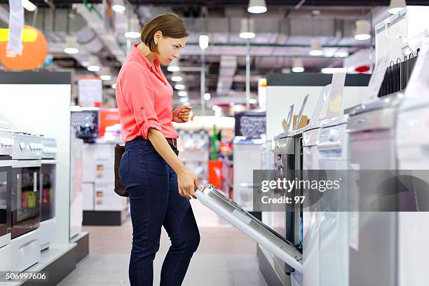 woman buys a dishwasher - electrical shop stock pictures, royalty-free photos & images