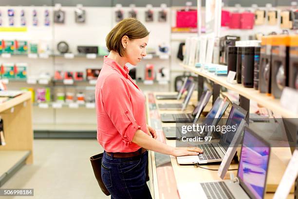 mulher escolhe o computador portátil - eletrodoméstico imagens e fotografias de stock