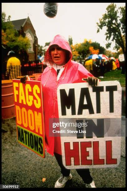 Woman w. Signs FAGS DOOM NATIONS & MATT IN HELL, 1 of anti-gay protesters at funeral for Matthew Shepard, gay 21-yr-old University of Wyoming student...