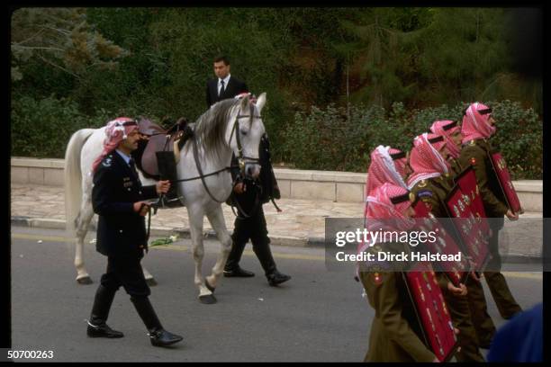 King Hussein's white horse being led during funeral procession for Jordanian monarch.