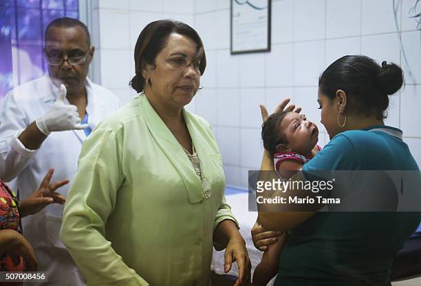 Lorrany Emily da Silva , who has microcephaly, is comforted after hospital staff drew her blood on January 26, 2016 in Recife, Pernambuco state,...