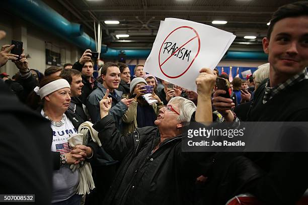 Protester flashes her middle finger as she is escorted out after interrupting a Republican presidential candidate Donald Trump campaign event at the...