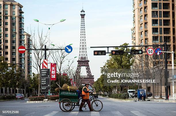 This picture taken on January 26, 2016 shows a street clearn crossing the street in front of a replica of the Eiffel Tower in Tianducheng, a luxury...