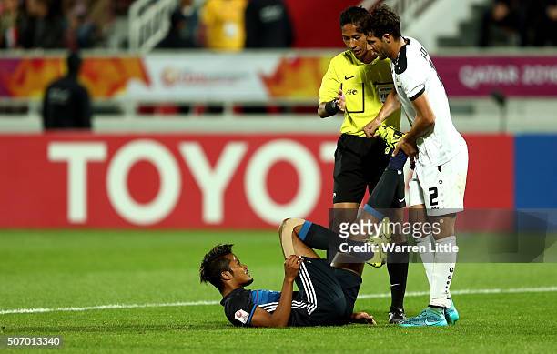 Musashi Suzuki of Japan is helped by Natiq Naji Suad of Iraq as he susstains an injury during the AFC U-23 Championship semi final match between...