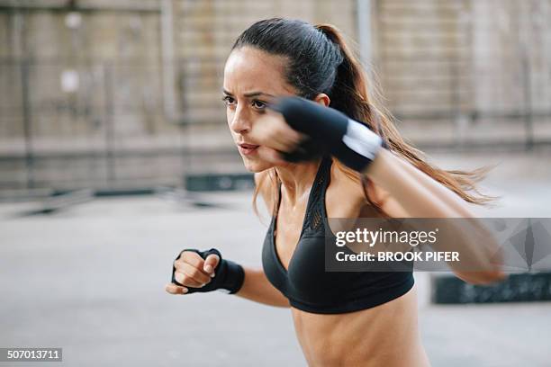 young woman boxing in urban setting - woman fighter stock-fotos und bilder