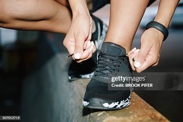 young woman tying athletic shoelace - cordón de zapato fotografías e imágenes de stock