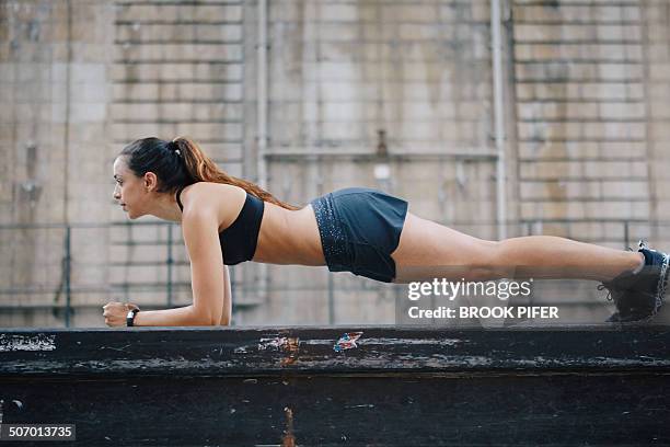 young woman doing plank core work in urban setting - flexiones fotografías e imágenes de stock