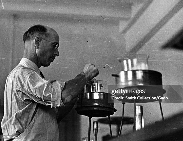 Scientist working with boiling beakers in a fermentation laboratory, Prince Georges County, Beltsville, Maryland, 1935. From the New York Public...