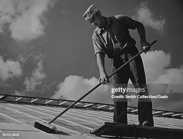Worker cleaning glass on top of an experimental greenhouse at the United States Department of Agriculture experimental farm, Beltsville, Maryland,...