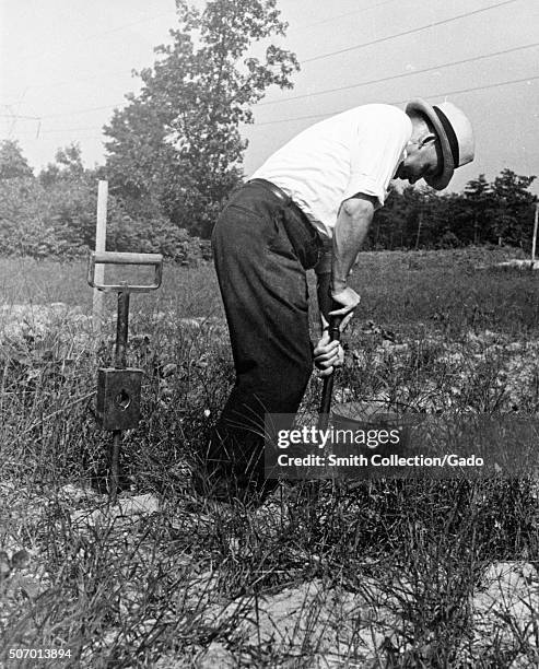 Worker performing a moisture test on soil at the United States Department of Agiculture experimental farm in Beltsville, Maryland, 1935. From the New...