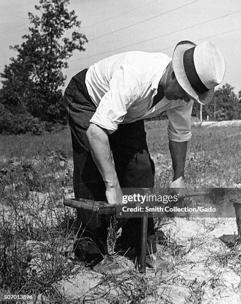 Worker performing a moisture test on soil at the United States Department of Agiculture experimental farm in Beltsville, Maryland, 1935. From the New...