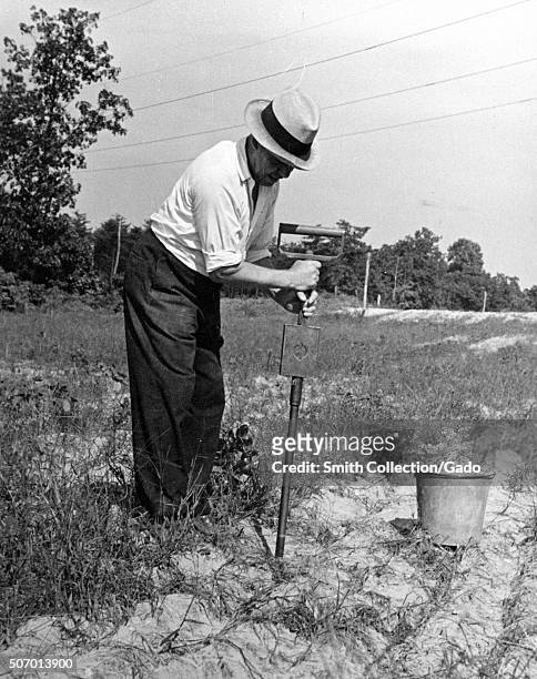 Worker performing a moisture test on soil at the United States Department of Agiculture experimental farm in Beltsville, Maryland, 1935. From the New...