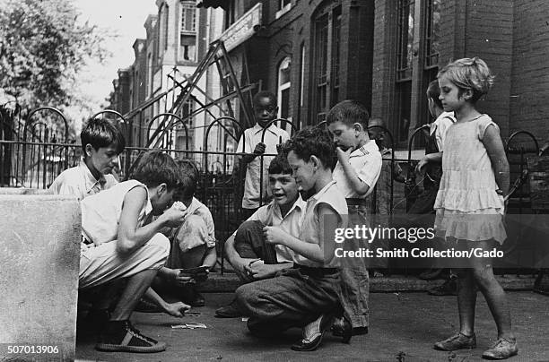 Children playing cards in front yard in slum area near Union Station, a section of town inhabited by both Caucasian and African-American residents,...